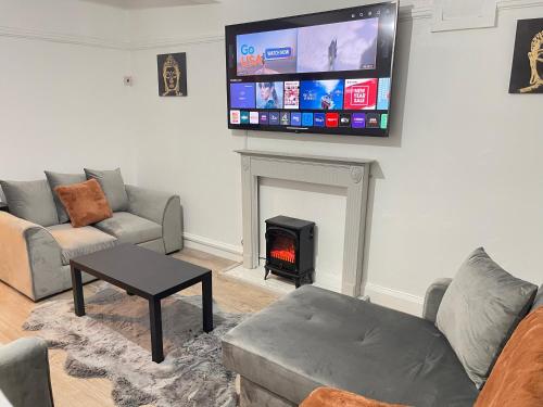 a living room with a fireplace and a tv on the wall at Easystays The Hidden Gem Large Basic Home Can Sleep 15 in Braunstone