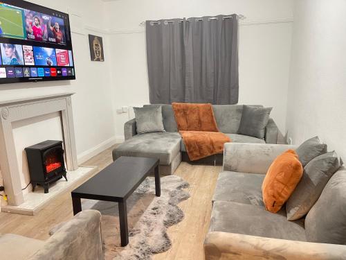 Hometel Hidden Gem Large Comfy Home Can Sleep 14 في Braunstone: غرفة معيشة مع أريكة ومدفأة