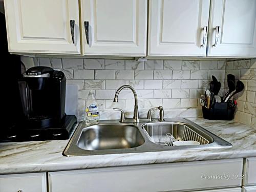 - un évier en acier inoxydable dans une cuisine avec des placards blancs dans l'établissement Lovely! near Cleve Clinic/UH/CWRU/Dwntwn w/porch, à Cleveland