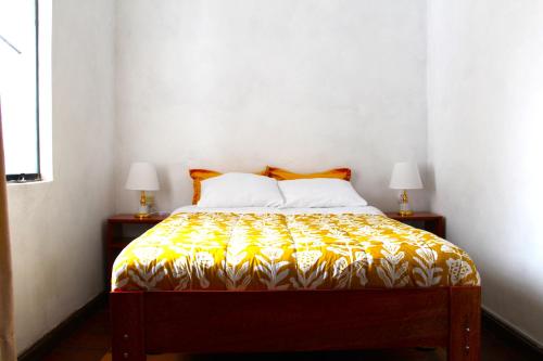 Schlafzimmer mit einem Bett mit gelber und weißer Tagesdecke in der Unterkunft Inti Wasi II in Cusco