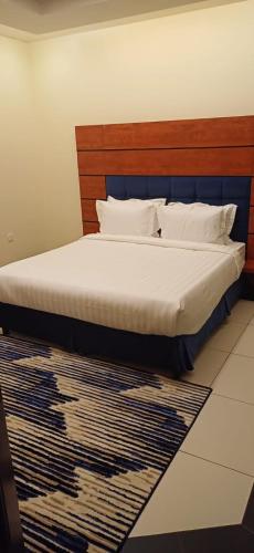 a bedroom with a bed with a wooden headboard and a rug at ريف الخرج 2 للشقق الفندقية in Al Kharj