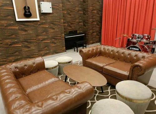 a living room with a leather couch and tables and a piano at Skytree A0802-(2) Nobles Room / Aeon in Johor Bahru