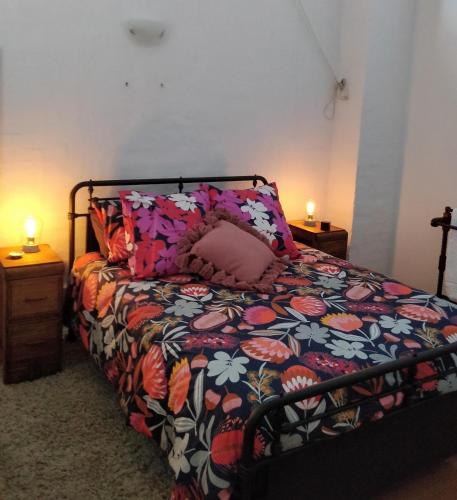 a bedroom with a bed with a floral comforter at Pips on Mitchell - Beautiful Historic Apartment in Bendigo