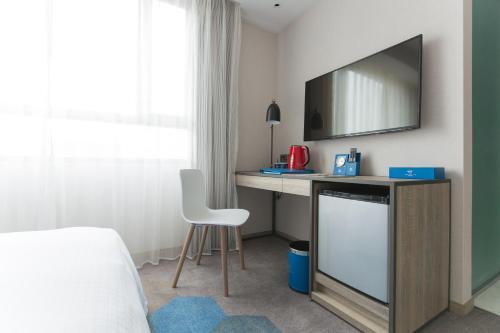 a bedroom with a desk with a tv and a chair at Airline Inn - Kaohsiung Station in Kaohsiung
