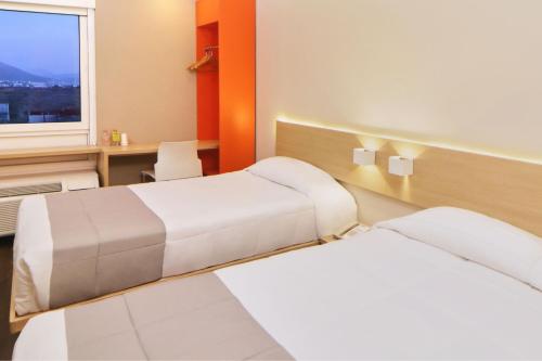 a room with two beds and a desk and a window at City Express Junior by Marriott Tijuana Otay in Tijuana