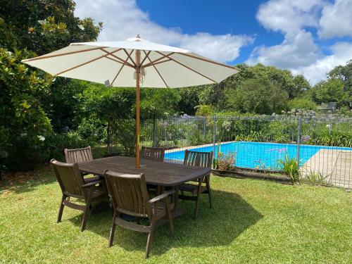 a table and chairs with an umbrella in the yard at Mission Retreat in Kerikeri