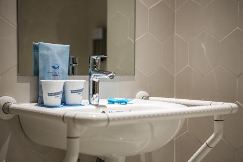 a bathroom sink with two cups and a faucet at Airline Inn - Kaohsiung Station in Kaohsiung