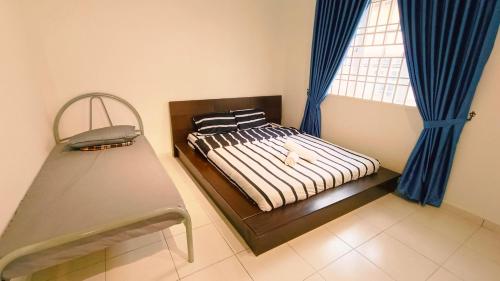 a bedroom with a bed with blue curtains and a window at 184 Kulai Homestay Tmn Gunung Pulai 3BR 9pax Shortstay in Kulai