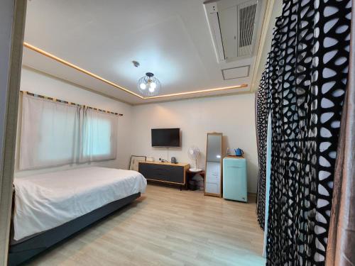 a bedroom with a bed and a desk and a tv at Wind Jeju Cafe & Pension in Seogwipo