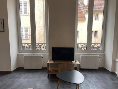 a living room with two windows and a tv at Le Navy Blue in Vesoul