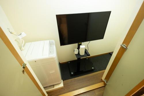 Elle comprend une télévision à écran plat installée sur un mur à côté d'un réfrigérateur. dans l'établissement 渋谷駅から6分/FREEWiFi/貸切マンション一室/33㎡/可做饭/中国語&韓国語&英語, à Tokyo