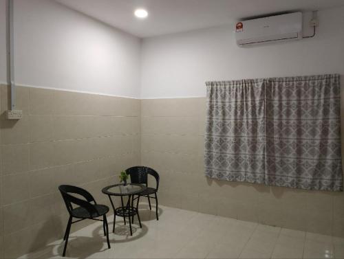 a room with a table and chairs and a window at Lawer Guesthouse (Pulau Langkawi) in Pantai Cenang