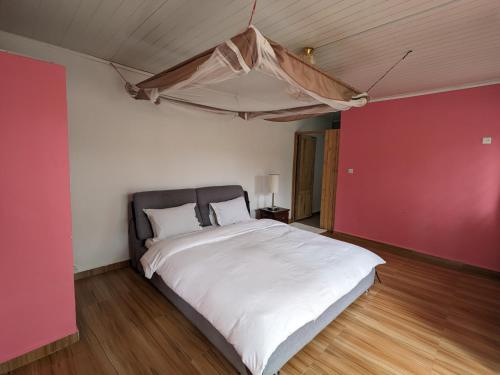 a bedroom with a large white bed with a red wall at OKA Forest Lodge in Andasibe