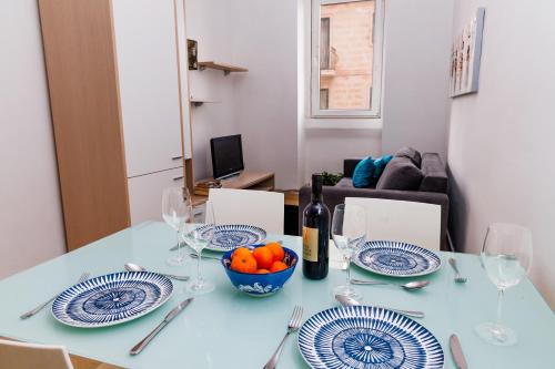a table with plates and wine glasses and a bowl of fruit at Stylish St Julians 2 bedroom apartment for rent in the city centre with Terrace in St. Julianʼs