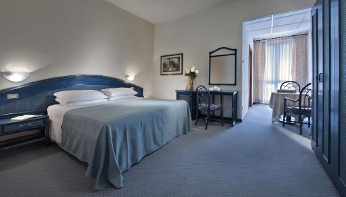 1 dormitorio con 1 cama grande, mesa y sillas en Hotel Terme Bologna, en Abano Terme