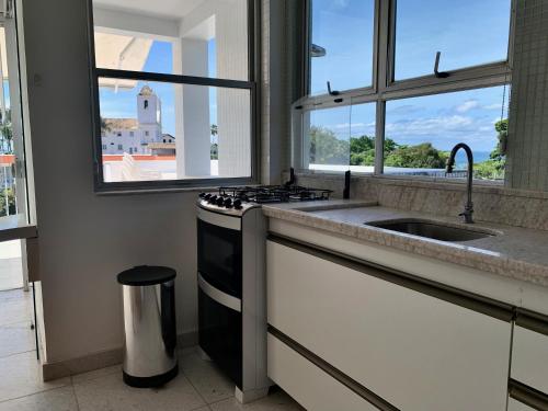 a kitchen with a stove and a sink and windows at Penthouse with private pool & amazing views in Salvador