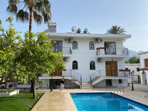 een vrouw staat voor een huis met een zwembad bij Templos Homes in Kyrenia