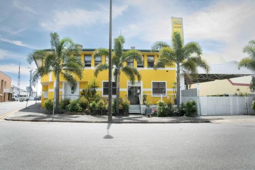 a yellow building with palm trees in front of it at Habitat Backpackers in Brisbane