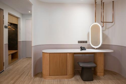 een badkamer met een wastafel met een spiegel en een kruk bij The Bayou Hotel Langkawi in Pantai Cenang
