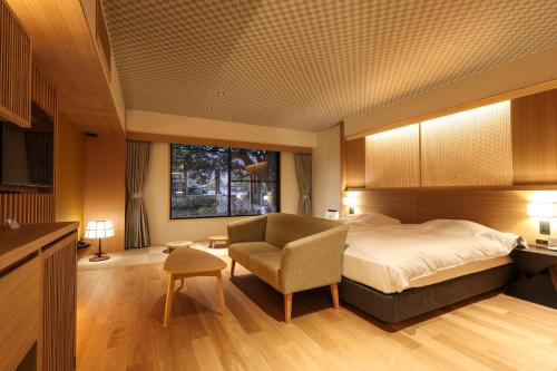 a hotel room with a bed and a chair at SPA TERRACE Shisui in Kobe