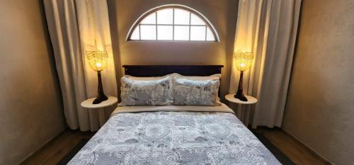 een slaapkamer met een bed met 2 lampen en een raam bij Cielo Guestfarm in Swartruggens
