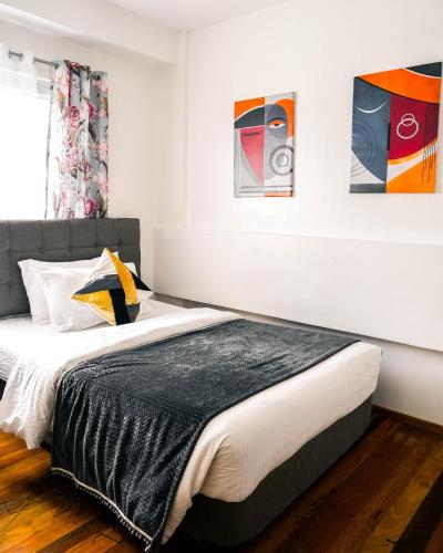 a bedroom with a bed and paintings on the wall at 87 Guesthouse in Baguio