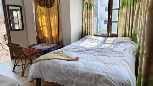 a bedroom with a bed and a chair and a window at Monkey Temple Homestay in Kathmandu