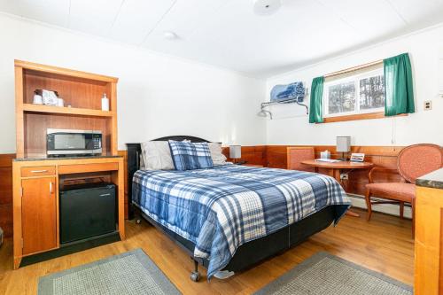 貝什爾的住宿－West Bethel Motel，一间卧室配有一张床、一台电视和一张桌子