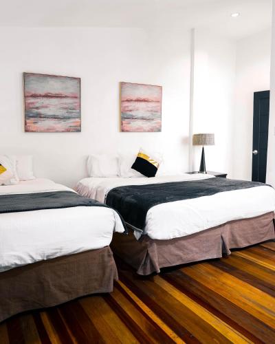 two beds in a room with wooden floors at 87 Guesthouse in Baguio