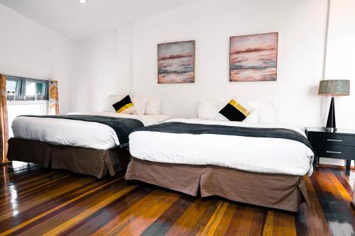 two beds in a white room with wooden floors at 87 Guesthouse in Baguio