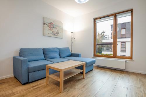 a living room with a blue couch and a table at Beach&Nature - Bursztynowa in Gdańsk