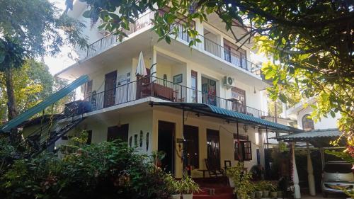 a large white building with a balcony at Little Swan Guest house in Bentota