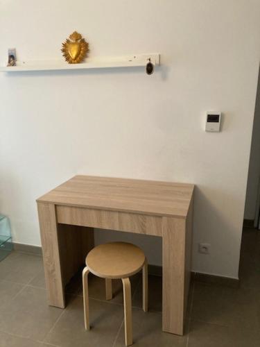 アヴィニョンにあるAvignon appartementの白壁の横に椅子付きの木製テーブル