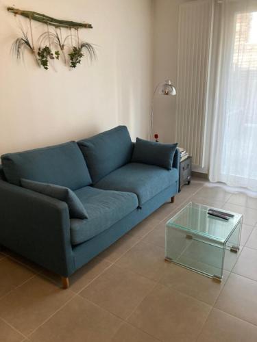 アヴィニョンにあるAvignon appartementのリビングルーム(ガラステーブル付)の青いソファ