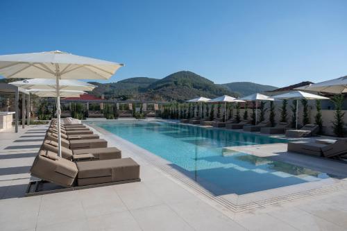 a swimming pool with lounge chairs and an umbrella at Oniro Boutique Hotel in Toroni