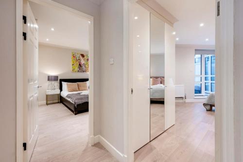 a room with a bedroom with a bed and a mirror at Stunning 2-bedroom-hosted by Sweetstay in London