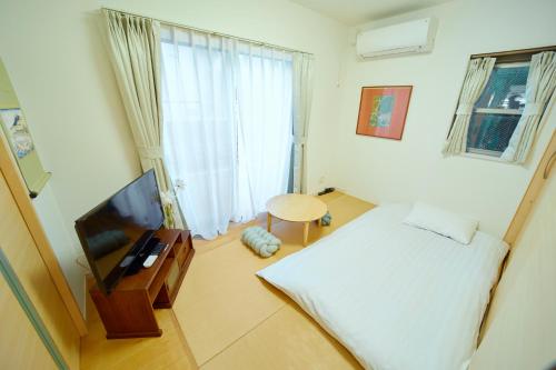 a small bedroom with a bed and a television at Shinjuku 'Deep Lane' Villa in Tokyo