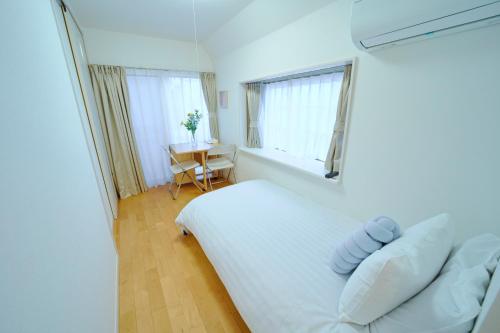 a bedroom with a white bed and a window and a table at Shinjuku 'Deep Lane' Villa in Tokyo