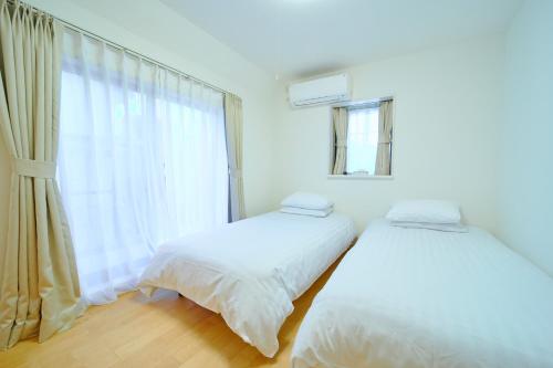a white room with two beds and a window at Shinjuku 'Deep Lane' Villa in Tokyo
