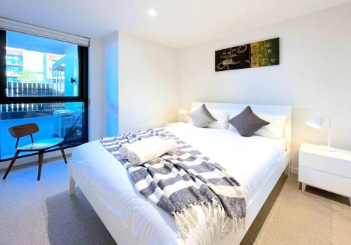 a white bedroom with a large bed and a window at Brilliant Quay Blvd Apt Close to Wyndham Harbour in Werribee South
