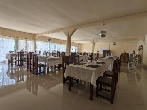 a dining room with white tables and wooden chairs at OKA Forest Lodge in Andasibe