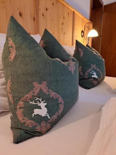 a bed with three pillows with a deer on it at Gasthof Stauder in Innsbruck