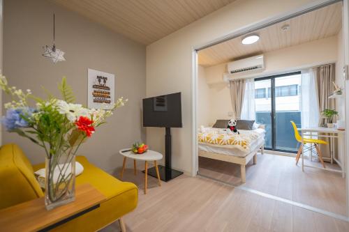 Hotel Story Namba في أوساكا: غرفة معيشة مع أريكة صفراء وغرفة نوم