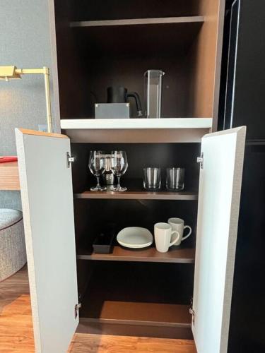 a cupboard with plates and utensils in it at Citadines Harbour Front Yokohama in Yokohama
