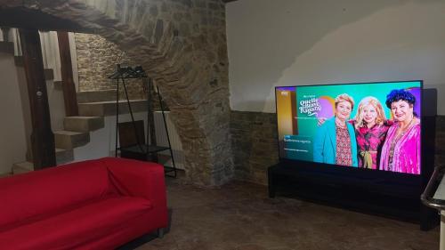 a flat screen tv in a living room with a red couch at Casa Al Plumbago in Termini Imerese