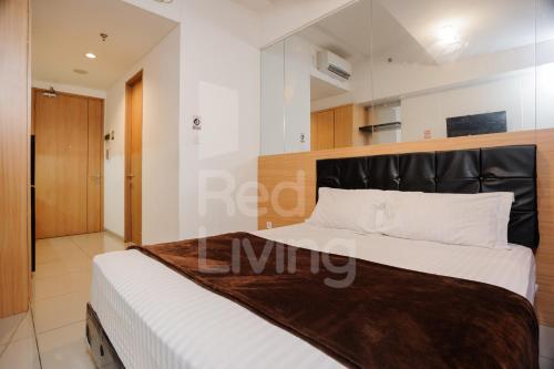 ein Schlafzimmer mit einem Bett mit schwarzem Kopfteil in der Unterkunft RedLiving Apartemen TreePark City - Hunian Idamanku Tower Alpine in Kebonnanas