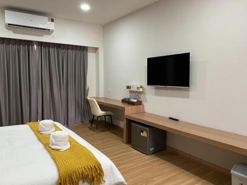 a hotel room with a bed and a desk with a television at ดิ อัยย์ชญา โฮเทล in Ban Phraek Sa