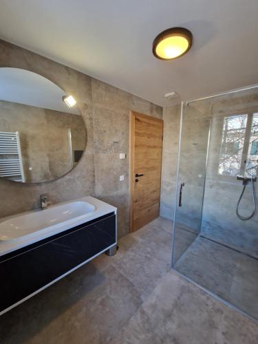 a bathroom with a tub and a glass shower at Appartements Marktplatzerl in Mauterndorf