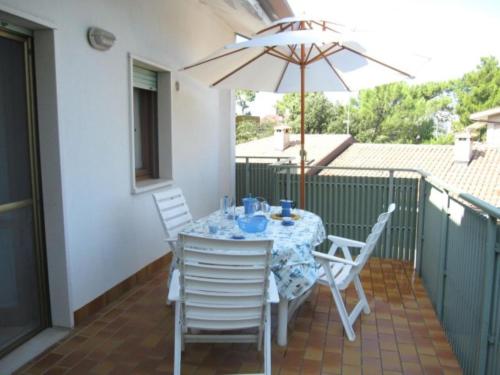 een tafel met stoelen en een parasol op een balkon bij Comfy flat with balcony at 30metres from the beach in Lido