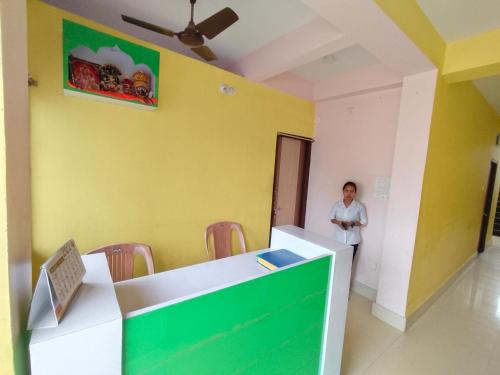 a woman standing in a room with a yellow wall at Shivangi Eco in Puri